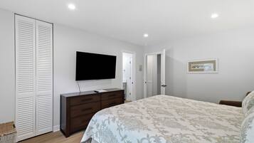 A bedroom with a bed, a dresser, a television, and a door.