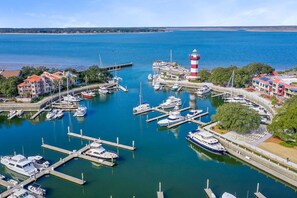 A marina with boats docked, a lighthouse, and buildings along the waterfront.