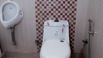 Un baño con inodoro, orinal y ducha.