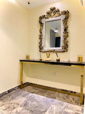 A bathroom with a marble floor, a gold-framed mirror, and a black countertop with a gold base.