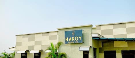 A building with a sign reading 'HAKOY BOUTIQUE HOTEL' and a paved entrance area.
