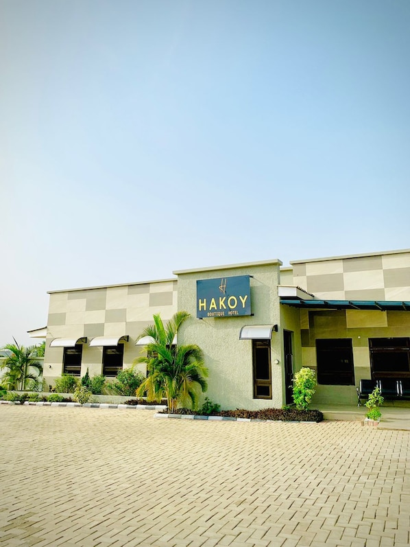 A building with a sign reading 'HAKOY BOUTIQUE HOTEL' and a paved entrance area.