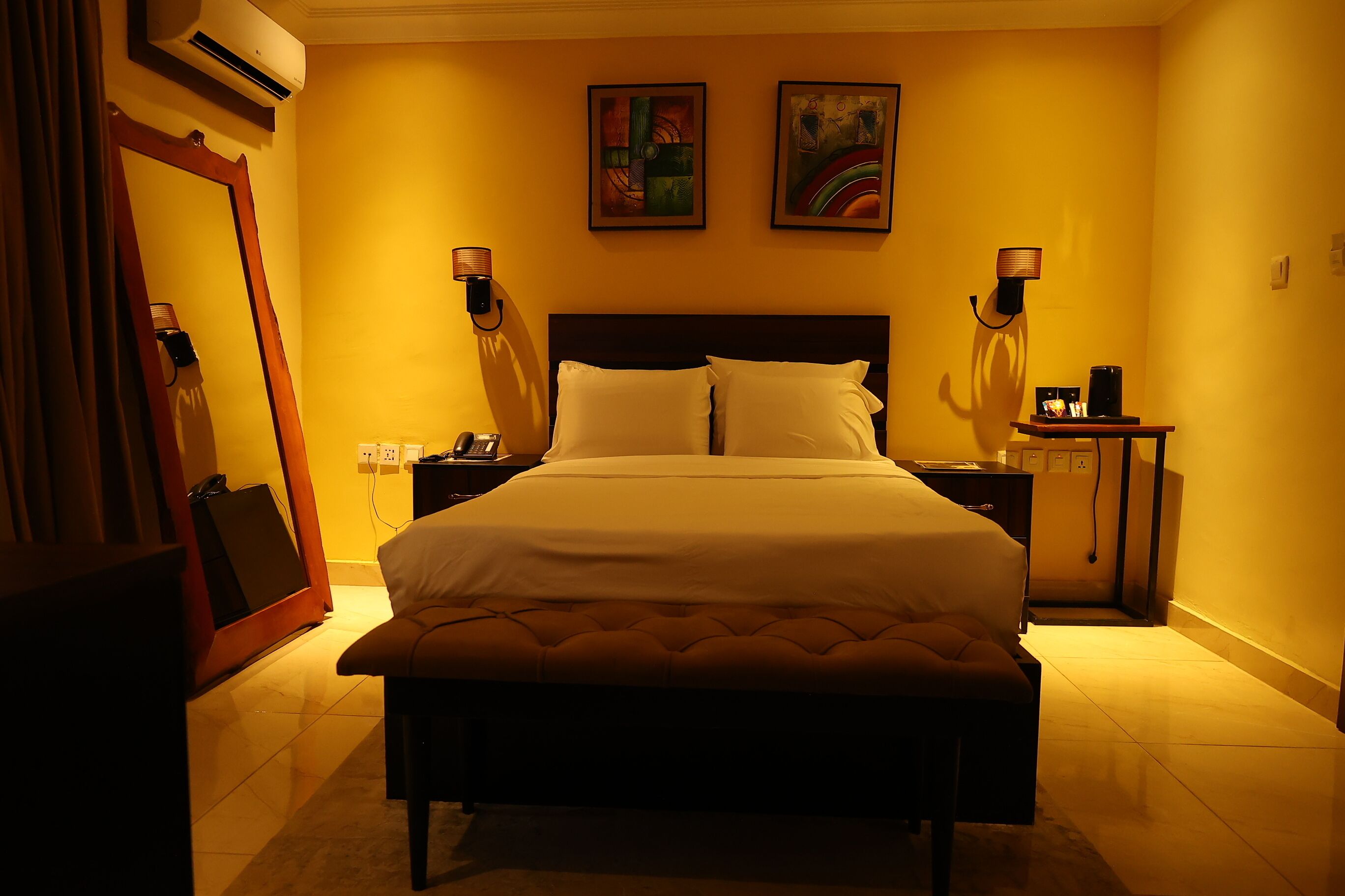 Una camera d'albergo con un letto grande, lampade sui comodini, un comodino, un tavolino e uno specchio.