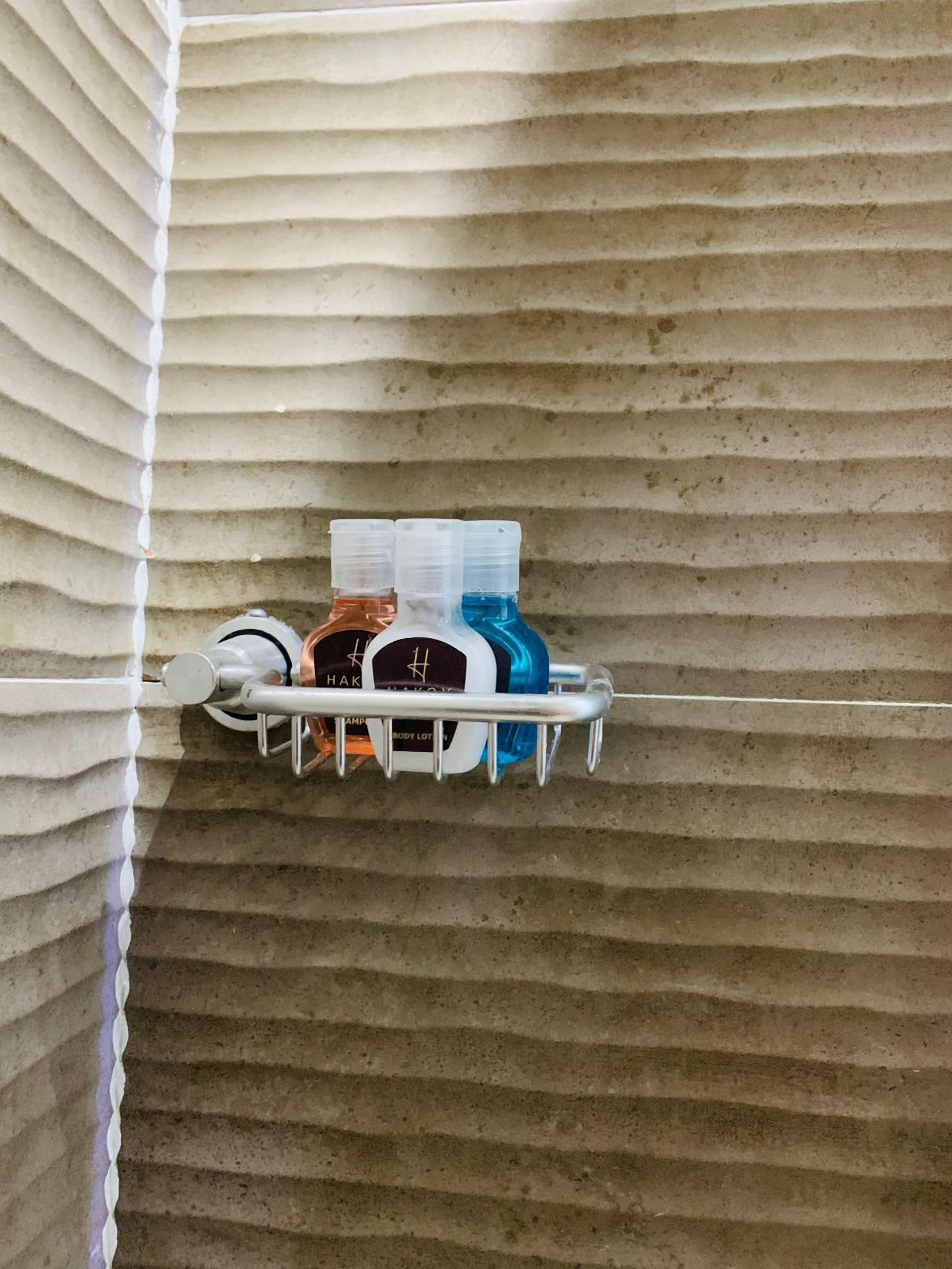 A bathroom with a striped wall and a metal rack holding toiletries.