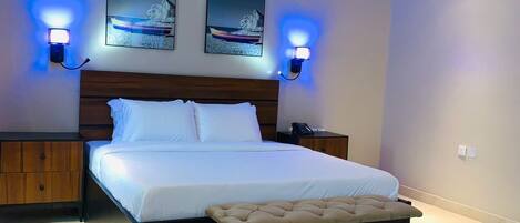 A modern bedroom with a large bed, bedside tables, an air conditioning unit, and wall-mounted lighting.
