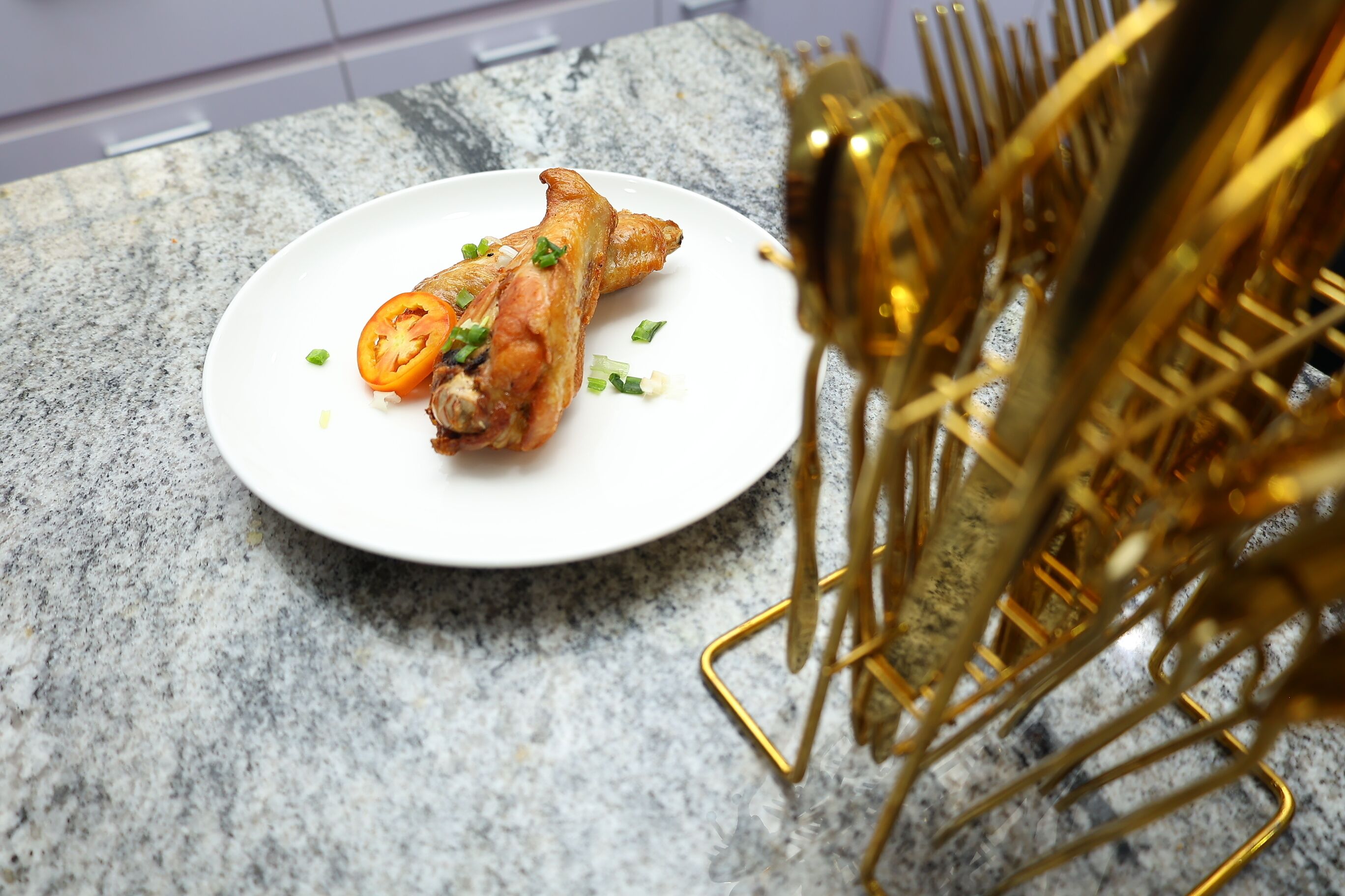 A plate of food on a granite countertop with a gold decorative stand in the background.