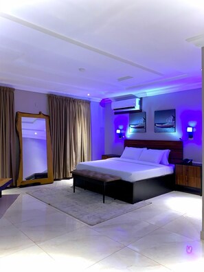 A modern hotel room with a large bed, a bedside table, a wardrobe, and a mirror.