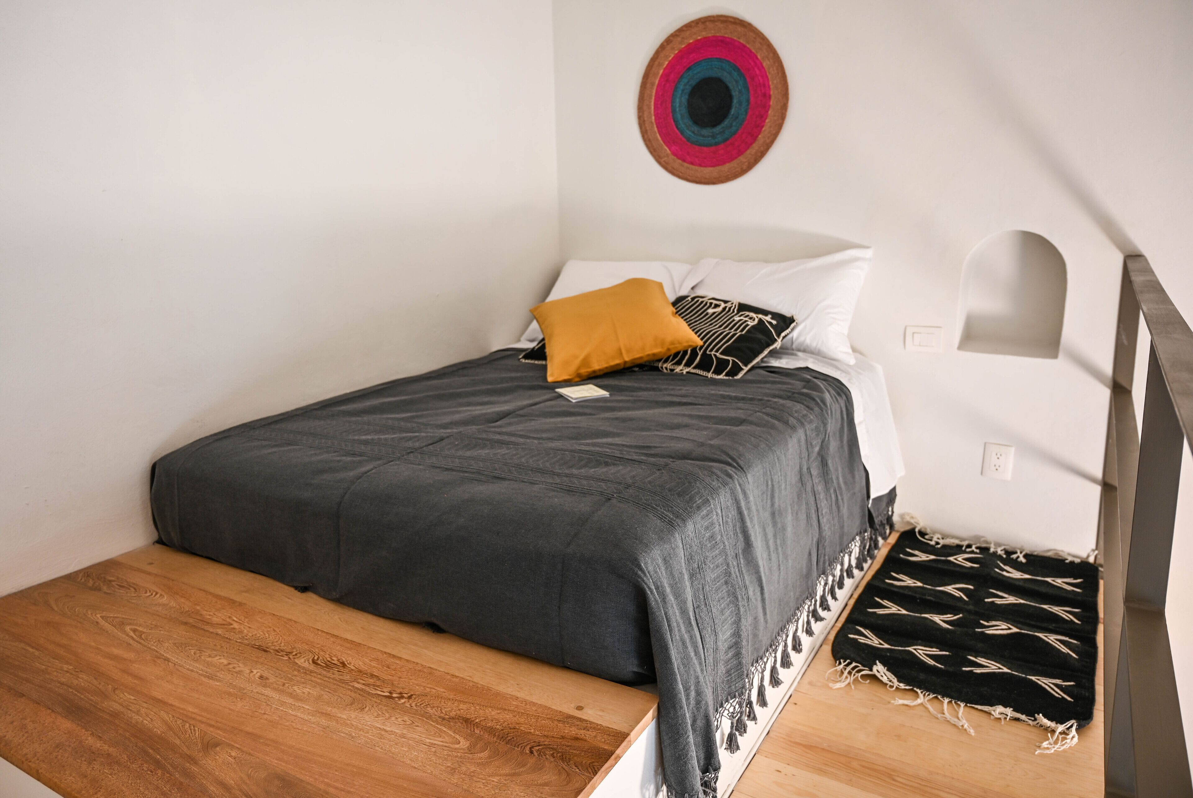 Une chambre à coucher comprenant un lit, un banc en bois, une lampe fixée au mur et un élément décoratif mural.
