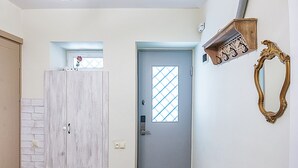 A hallway with a wooden bench, a door with a window, and a ceiling fan. - H&B apartments Ierusalim (Tbilisi)