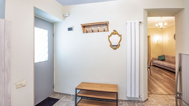 A room with a wooden bench, a radiator, a sofa, and a chandelier. - H&B apartments Ierusalim (Tbilisi)