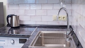 A kitchen with a stainless steel sink, a kettle, and a washing machine. - H&B apartments Ierusalim (Tbilisi)
