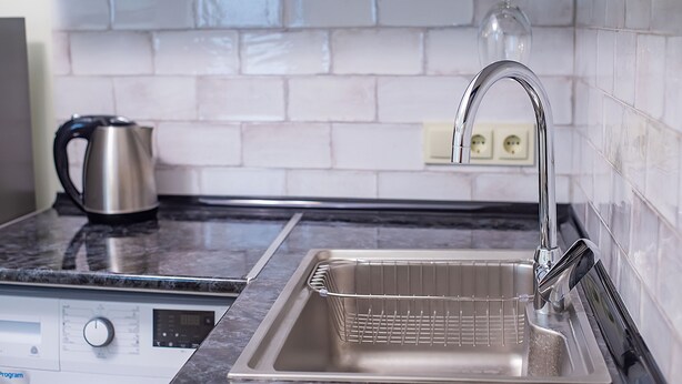 A kitchen with a stainless steel sink, a kettle, and a washing machine. - H&B apartments Ierusalim (Tbilisi)