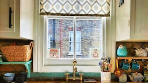 A kitchen with a window, a sink, and various kitchen items on the counter. - Charming London With Balcony (London)