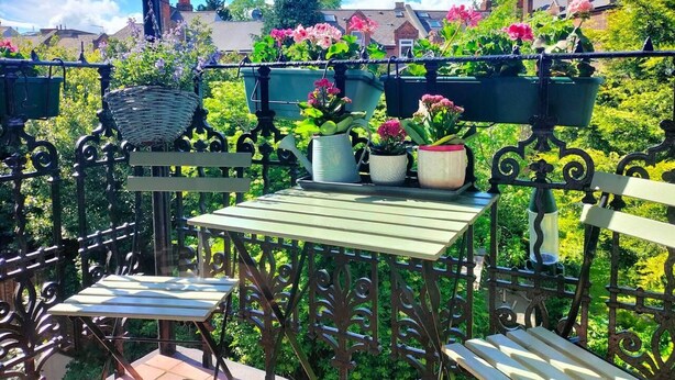 A balcony with a table and chairs, surrounded by potted plants and flowers. - Charming London With Balcony (London)