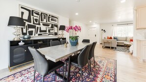 A dining area with a long table, black chairs, a patterned rug, and a decorative plant. - Beautifully Remodeled-Newly Furnished-Cozy, Colorful & Eclectic Home in N OKC!  (Oklahoma City)