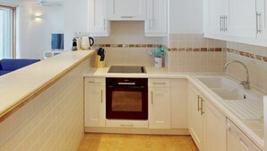 A compact kitchen with white cabinets, a built-in oven, a sink, and a countertop.
