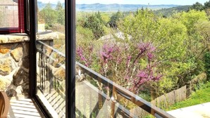 Un balcon offrant une vue sur un paysage montagneux, avec des murs en pierre et une balustrade en bois.