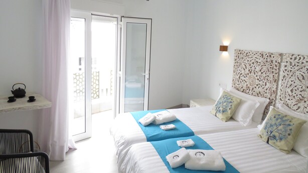 A hotel room with a bed, a small table with a kettle and cups, a chair, and a view of the outside through a sliding door. - Hotel Lua Isla Del Hierro (El Pinar de El Hierro)