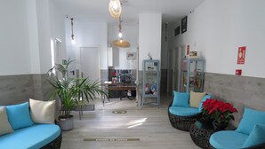 A spacious lobby with a reception desk, seating area with blue and beige cushions, a potted plant, and a sign on the floor. - Hotel Lua Isla Del Hierro (El Pinar de El Hierro)