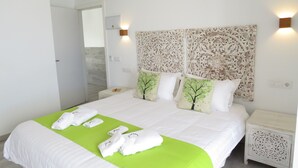A neatly made bed with green bedspread and white pillows, a wooden nightstand with intricate carvings, and a wall-mounted light fixture. - Hotel Lua Isla Del Hierro (El Pinar de El Hierro)
