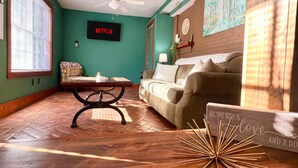 Ein gemütliches Wohnzimmer mit grüner Wand, einem Netflix-Schild, einem Holztisch, einer Couch und einer dekorativen Stern.