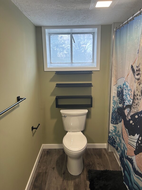 Un baño con inodoro, ventana y cortina de ducha con diseño de olas.