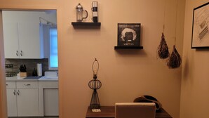 Comedor con mesa, silla, lámpara colgante y estanterías de pared con utensilios de cocina.