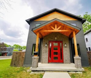 A two-story house with a red door, a stone foundation, and a wooden porch. - Bar/Billiards/Lounge/Near Mass (Indianapolis)