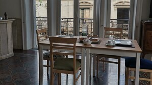 A dining area with a table set for four, large windows, and a patterned floor. - Ace Rooms Vsg (Villa San Giovanni)