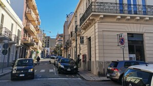 A street with parked cars, a building with a balcony, and a clear blue sky. - Ace Rooms Vsg (Villa San Giovanni)