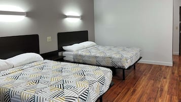 Habitación de hotel con dos camas, cada una con una colcha estampada, un cabecero oscuro y una lámpara fijada a la pared.