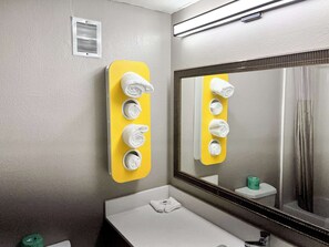 A bathroom with a yellow towel rack, a large mirror, and a white sink.