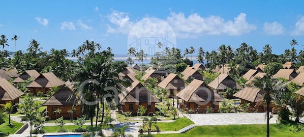 A resort with multiple bungalow-style buildings, a swimming pool, and palm trees. - Lindos Bangalôs no Eco Resort  (Tamandaré)