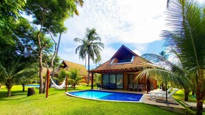 A resort with a swimming pool, a covered patio, and palm trees.