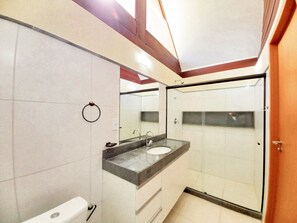 A modern bathroom with a large mirror, a sink, and a shower.