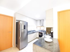 A modern kitchen with stainless steel appliances, white cabinetry, and a granite countertop. - Lindos Bangalôs no Eco Resort  (Tamandaré)