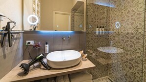 A modern bathroom with a round mirror, a sink, and a handheld hair dryer on the counter.