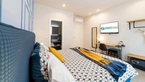 A hotel room with a bed, a desk, a TV, and a wardrobe.