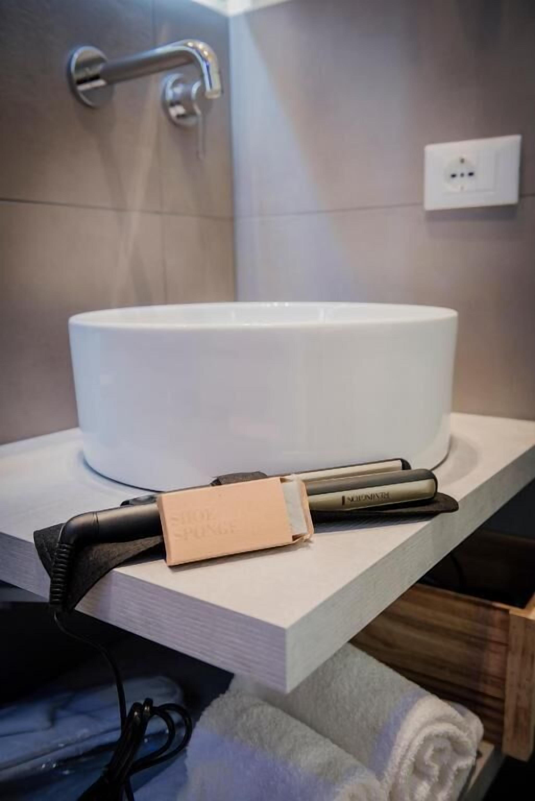 Une salle de bain avec un lavabo blanc, un porte-serviettes et une prise électrique au mur.