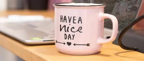 A white mug with "HAVE A NICE DAY" text on a wooden desk.
