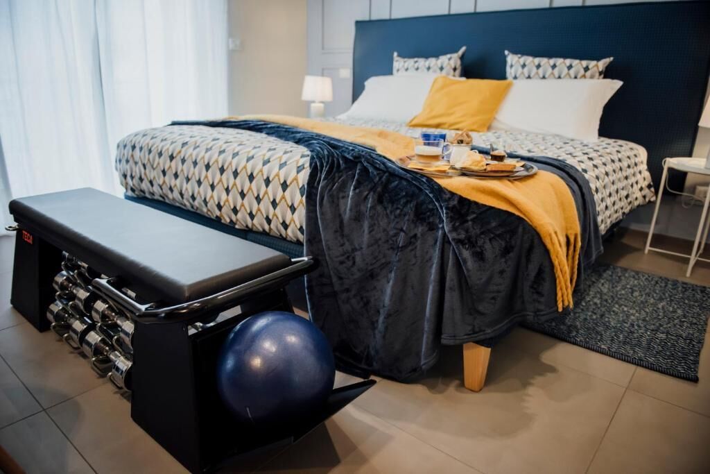 Une chambre à coucher bien rangée, avec un lit, une table de chevet et un banc avec des poids.