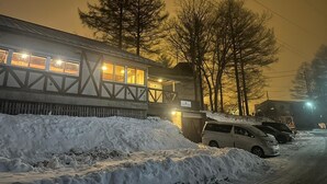 Un edificio con el suelo cubierto de nieve y coches estacionados.