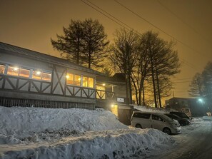 A building with a snow-covered ground and parked cars.