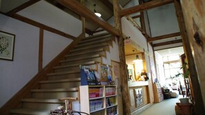 Una escalera de madera que lleva a una zona de descanso con una estantería y una lámpara.