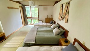 Habitación de hotel con dos camas, cabecero de madera, mesita de noche, cómoda y ventana con cortinas.