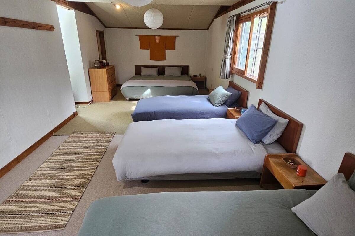 A bedroom with two beds, a wooden dresser, and a hanging light fixture.