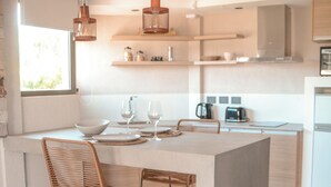 Une cuisine moderne dotée d’un îlot central, de tabourets de bar, de luminaires suspendus et offrant une vue sur l’extérieur.