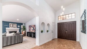 A spacious hallway with a fireplace, a dark wooden door, and a living area with a sofa and a TV. - Luxury Scottsdale Retreat! Heated Pool | Mini Golf (Scottsdale)