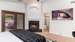A bedroom with a fireplace, a bed, a ceiling fan, and a large painting. - Luxury Scottsdale Retreat! Heated Pool | Mini Golf (Scottsdale)