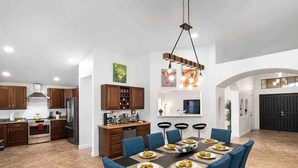 A spacious kitchen with modern appliances, a dining area with blue chairs, and a large dining table set for a meal. - Luxury Scottsdale Retreat! Heated Pool | Mini Golf (Scottsdale)